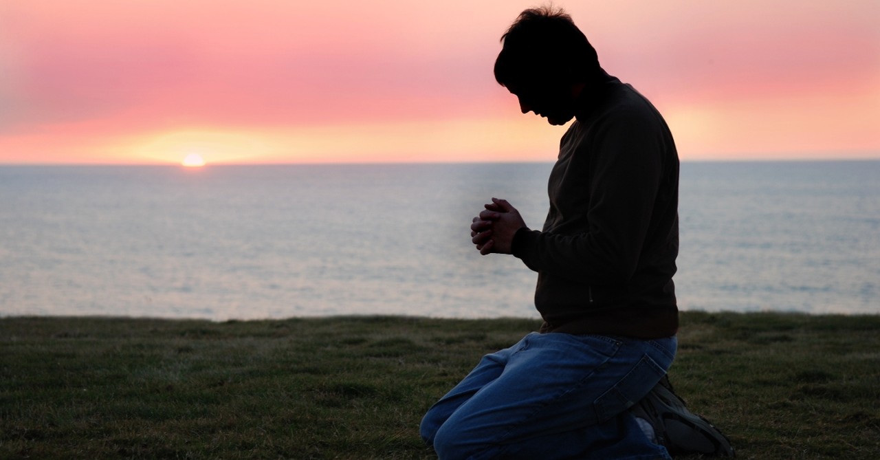 Man kneeling in Prayer at sunset