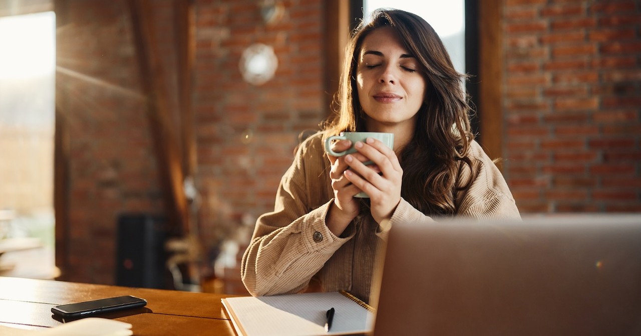 Woman closed eyes drinking coffee working praying laptop