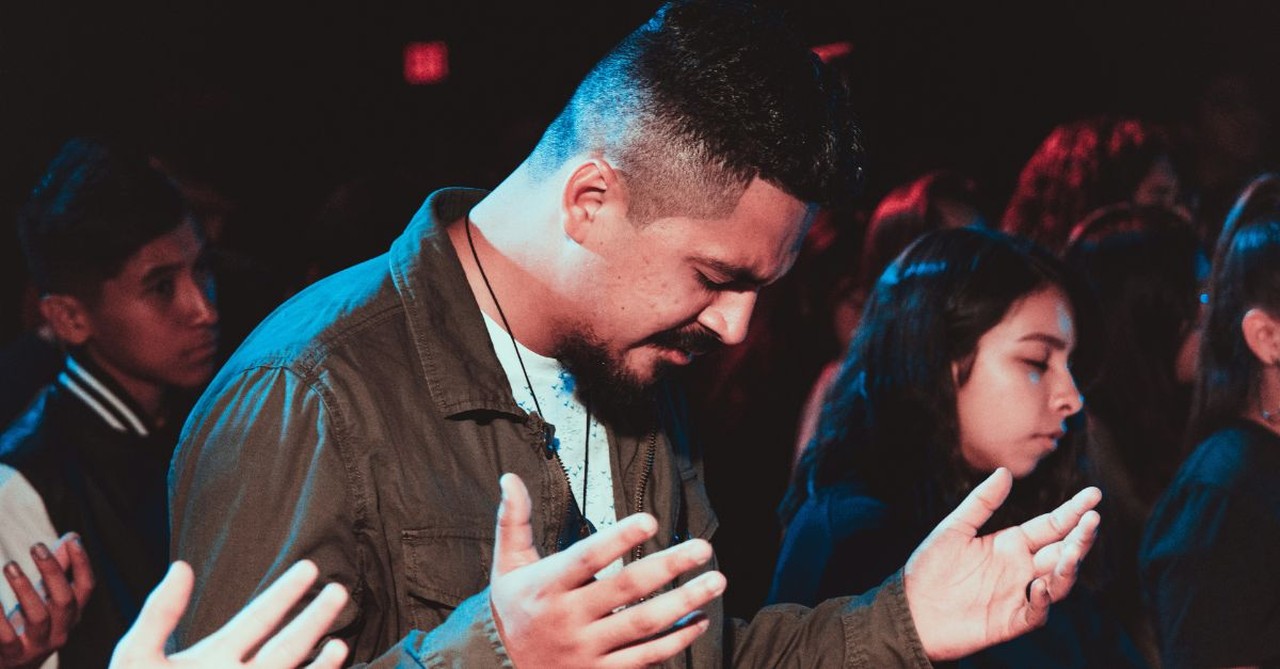 Man praying in a  crowd; why do Christians pray?