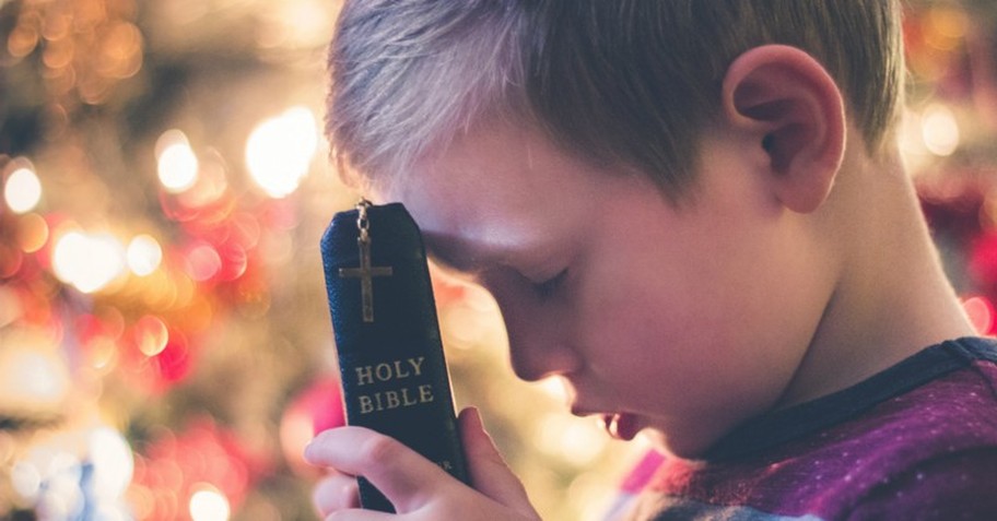 child praying with bible and cross; christmas eve prayer