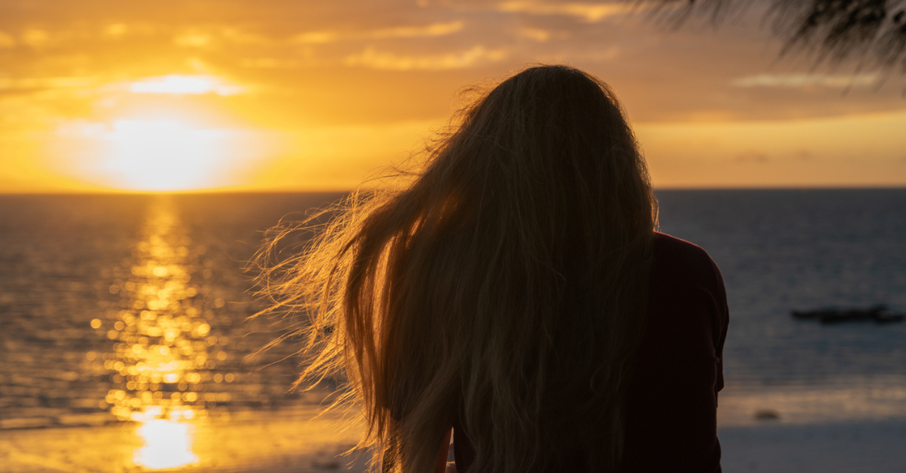 Woman watching the sunrise/sunset; a Father's Day prayer for those far from their dads.