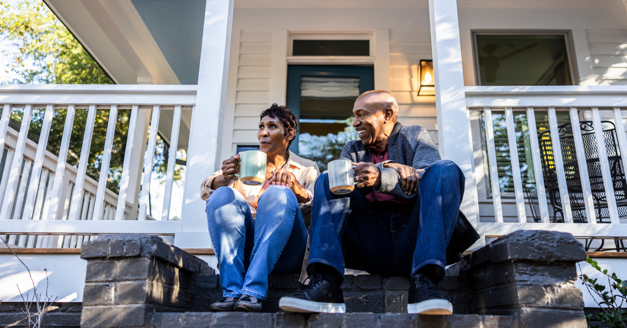Older married couple drinking coffee on porch home house