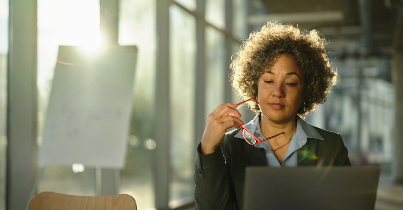An office worker diligently focusing at a desk with sunlight streaming in.